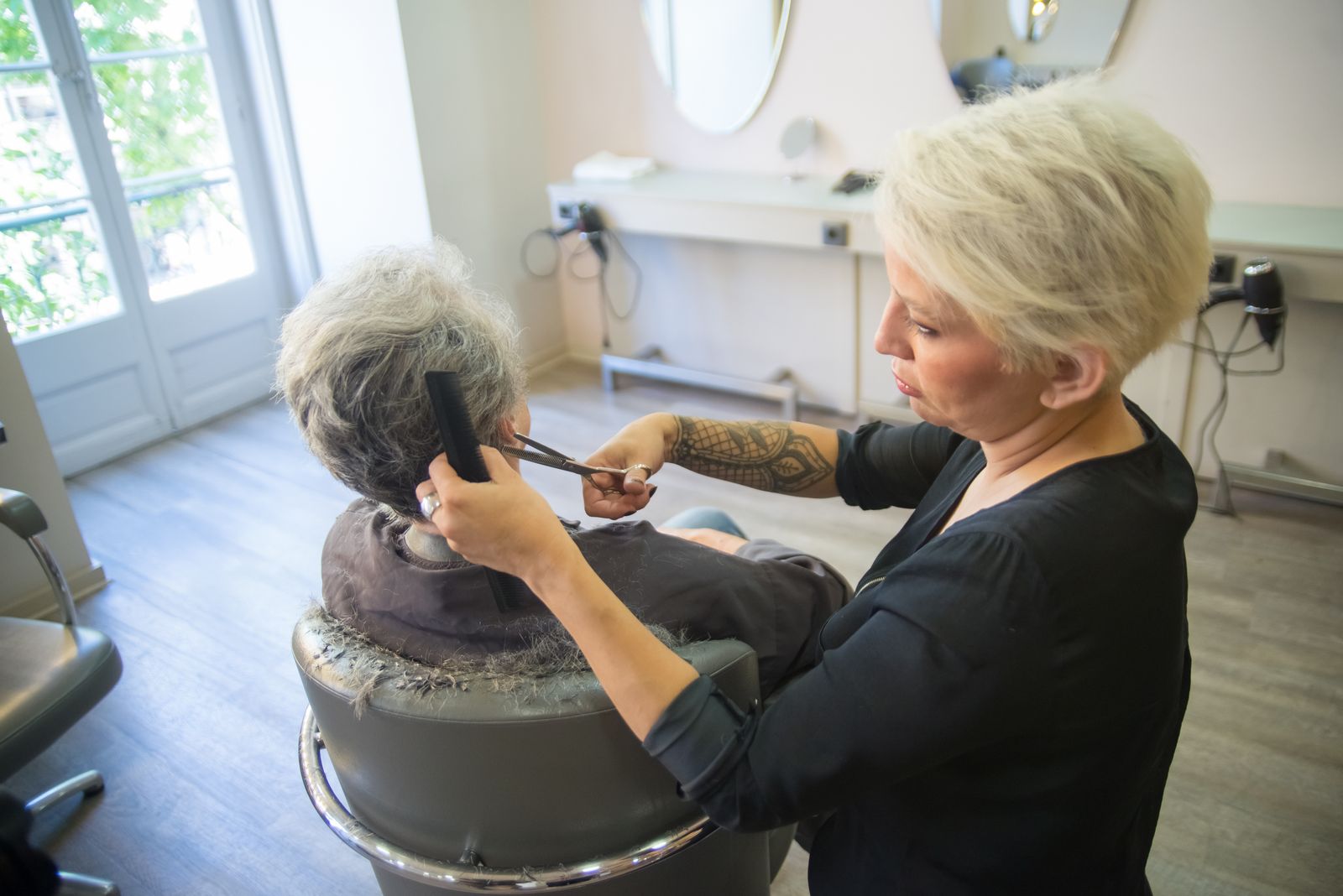 Coiffeuse en formation réalisant une coupe technique