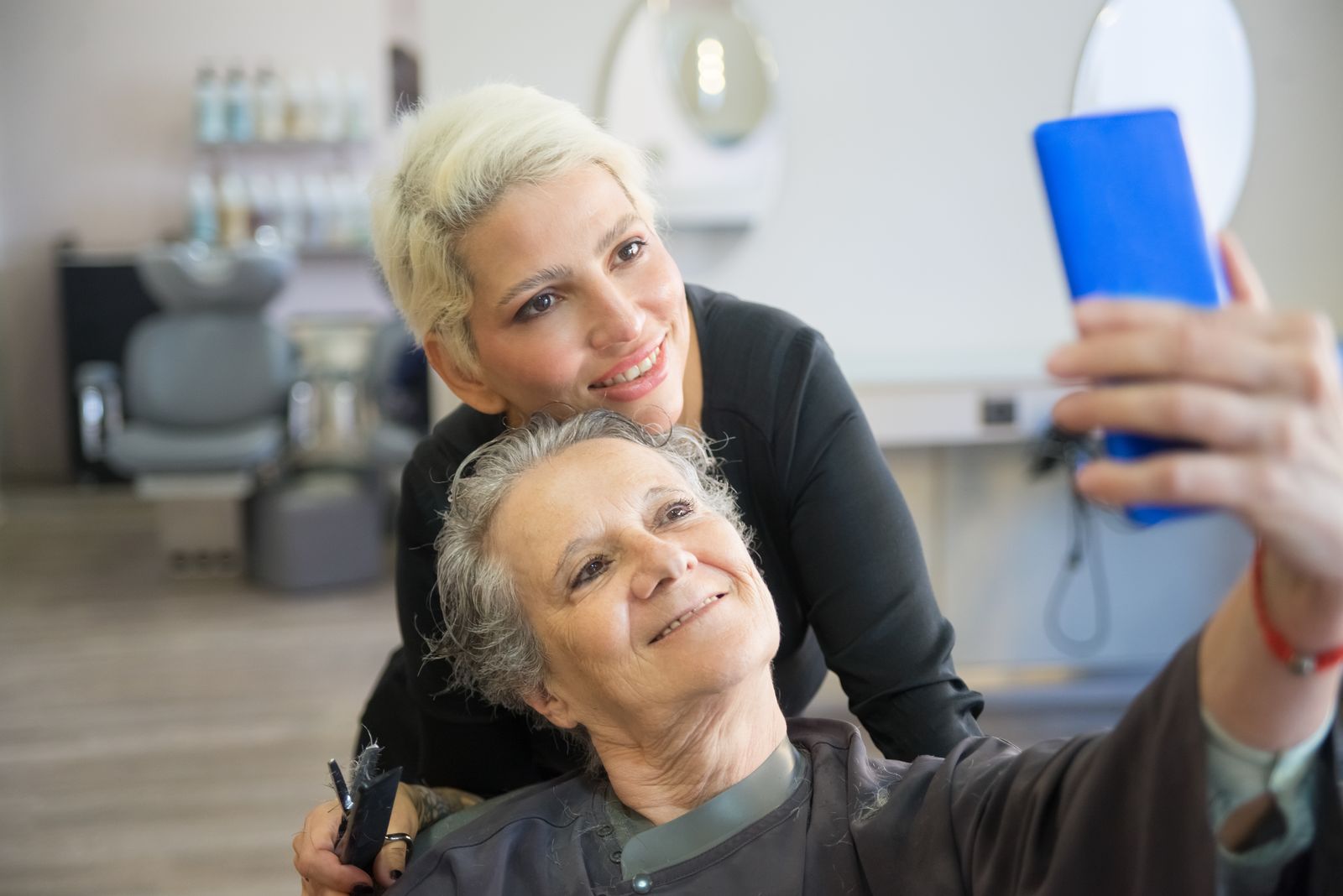 Coiffeuse et cliente prenant un selfie en salon pour les réseaux sociaux